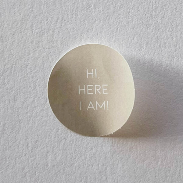 Beige sluitzegel, witte tekst ‘HERE I AM'